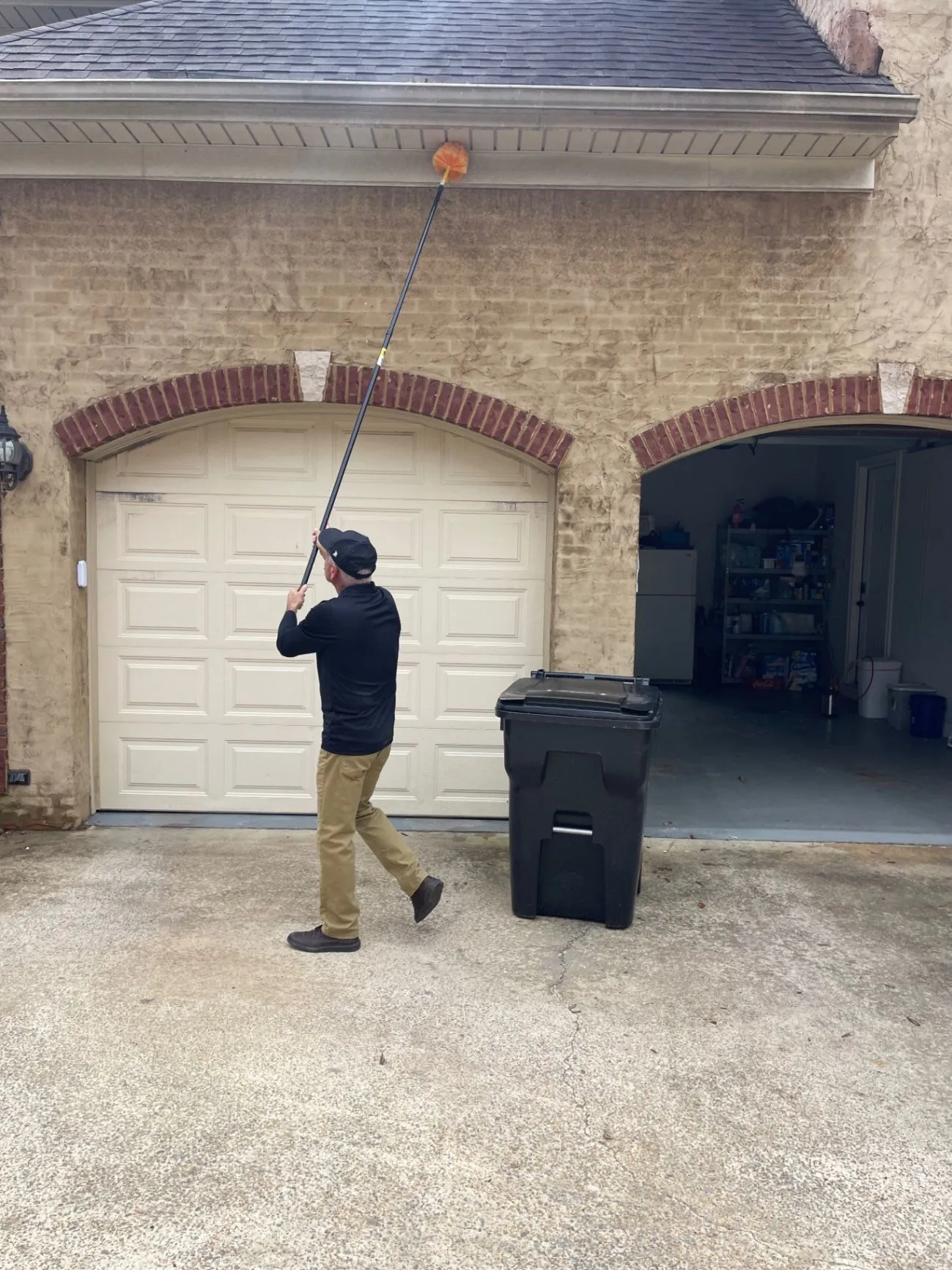 Scott Gilbert removing spider webs from the exterior of a Dora, Alabama home with a de-webbing tool.
